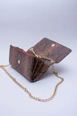 Cartera tipo sobre color beige con textura granulada y correa de cadena dorada.