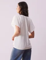 Blusa blanca texturada, marca Sabrina Lauren, con cuello a la base, escote en V con puntilla y lazo, mangas cortas amplias y aplique de puntilla.