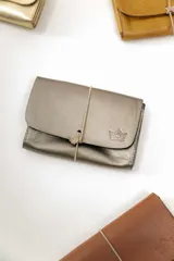 Billetera tipo sobre de cuero negro con cierre de elástico, separaciones internas y bolsillo con cierre para monedas.