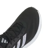 Championes de running Adidas Supernova 3, color negro con detalles en blanco. Presentan una parte superior de malla transpirable, acolchado en la lengüeta y el talón, mediasuela con amortiguación Bounce y Boost, y suela de goma.