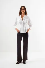 Camisa de manga larga color azul con finas rayas verticales blancas. Presenta cuello mao, botones frontales y dos bolsillos de parche con tapa en el pecho. La prenda tiene un diseño ajustado en la cintura con pinzas y un volumen holgado en las mangas.