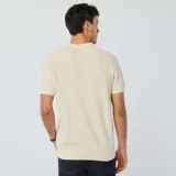 Remera polo de punto color crudo con cuello clásico, manga corta y cierre con botones de madera.