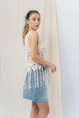 Top tejido artesanal color crudo, confeccionado en punto calado con diseño protagonista. De silueta recta y calce relajado, presenta escote amplio y terminación inferior con flecos.