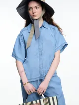 Camisa negra de manga corta confeccionada en denim liviano de tencel, de calce cuadrado y relajado. Presenta cierre frontal con tapeta escondida y costuras en color contraste.