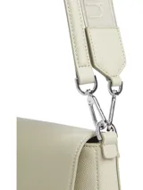 Cartera de hombro color crema, marca Calvin Klein, modelo CK Must. Tiene correa de hombro ajustable con el logo de la marca y otra correa más fina.