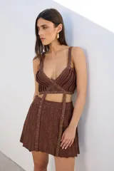 Top negro con lurex, de breteles finos y corte irregular con tiras cruzadas en el abdomen.