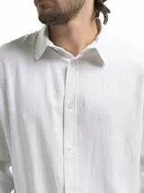 Camisa de manga larga, color blanco, con cuello camisero y botones frontales. El tejido presenta una textura visible de lino.