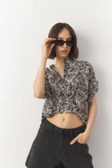 Blusa de manga corta con estampado de hojas en tonos negro y blanco, con cuello mao y botones a tono.