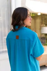 Vestido camisero de muselina color negro, de largo midi, con cuello clásico, manga corta y cierre frontal con botones.