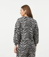 Blusa de viscosa con estampado animal print en blanco y negro, escote en V, mangas largas abullonadas con puños ajustados y dobladillo mullet.