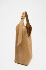 Bolso tipo saca de cuero color marrón claro, con asa de hombro ajustable y cierre imantado. Incluye cartera interior con cierre de cremallera metálica.