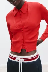 Chaqueta de punto roja con escote pico y manga larga. Tiene vivos laterales combinados a contraste y cierre frontal con botones forrados a tono.