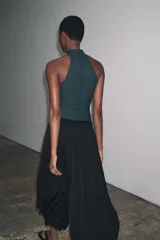 Top negro de cuello halter con cierre de botones en la parte trasera del cuello y espalda descubierta.