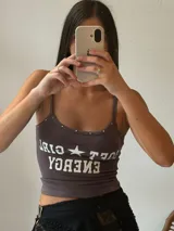 Musculosa corta gris con estampado de letras blancas y tachas plateadas en el escote.