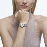 Reloj Swarovski Attract con caja redonda en tono oro champán y esfera guilloché plateada. El bisel y la correa metálica están engastados con cristales transparentes.