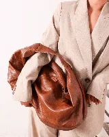 Bolso tipo hobo de cuero sintético color marrón, con forma ovalada y asa corta.