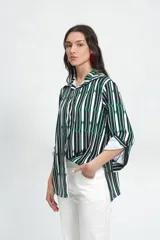 Camisa de manga larga con cuello clásico y estampado de líneas verticales en blanco, negro y verde. Corte holgado, mangas con pinzas laterales y puños anchos.