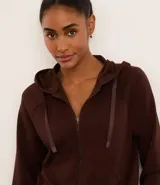 Campera deportiva marrón de modal, con capucha ajustable con cordón, cierre frontal con cremallera y bolsillos laterales.