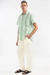 Pantalón de lino color crema, de corte recto y fit relajado. Tiene cintura elástica con cordón de algodón, bolsillos laterales y traseros.