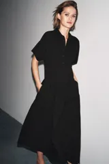 Vestido midi de algodón color negro, con cuello solapa, manga corta y falda evasé. Cierre frontal con botones y lateral con cremallera oculta.