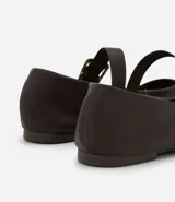 Zapatilla tipo bailarina de cuero color marrón, con punta redondeada y tira sobre el empeine con hebilla metálica dorada. Posee un tacón bajo de 1 cm y diseño clásico.