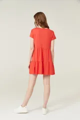 Vestido corto lila con cuello en V y mangas cortas. Tiene corte holgado y dos volados en la falda.