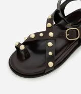 Sandalia plana marrón con dedera, punta redonda, aplicación de esferas doradas y hebillas doradas contrastantes.