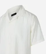 Camisa boxy de hombre confeccionada en viscolino color crudo con rayas texturizadas, cuello inglés, solapa, mangas cortas y abotonado frontal.