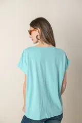 Blusa italiana color celeste con bordado de plumas al tono en el frente, confeccionada en lino y algodón.