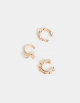 Set de tres cuffs dorados para la oreja con diferentes diseños: uno con forma de cadena, otro con forma de moño y otro con pequeñas esferas.