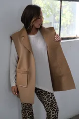 Chaleco largo color beige, con solapas y bolsillos delanteros con borde de corderito.
