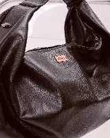 Bolso marrón oscuro de cuero sintético con forma ovalada y asa corta.