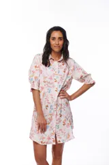 Vestido corto tipo camisero con estampado floral en tonos rosados, celestes y marrones. Tiene cuello camisero, mangas 3/4 abullonadas y cierre frontal con botones.