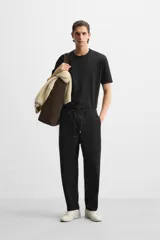 Pantalón de hombre color beige, corte carrot fit, con cintura elástica ajustable con cordón, bolsillos frontales y bolsillo trasero de plastrón.
