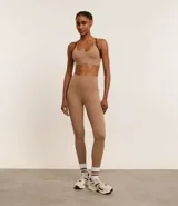 Calza deportiva color café, de microfibra ligera, tiro alto y corte ajustado. Cuenta con elástico en la cintura y tiras porta remera en la espalda.