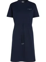 Vestido azul marino de algodón orgánico, corte recto, largo a la rodilla, cuello redondo, mangas cortas y cintura ajustable con cordón. Logo de Tommy Hilfiger bordado en el pecho y en la manga.