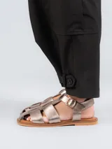 Sandalias bajas doradas con diseño de tiras entrecruzadas y hebilla lateral.