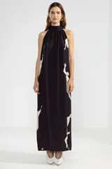 Vestido largo negro con estampado de sirenas color crema, cuello halter y corte evasé.