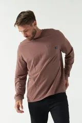 Remera color marrón de manga larga, con bolsillo en el pecho y logo de la marca en etiqueta sobre el bolsillo.