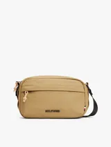 Bandolera Tommy Hilfiger color beige con logo texturizado en el frente. Tiene correa ajustable de tejido trenzado, cierre de cremallera y bolsillo exterior con cremallera.