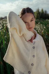 Cárdigan tejido en boucle color crudo, de corte holgado y mangas largas.