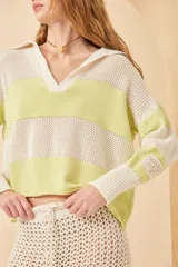 Sweater de punto a rayas horizontales color crema y azul marino, con cuello polo blanco y mangas largas. Tejido de algodón calado.