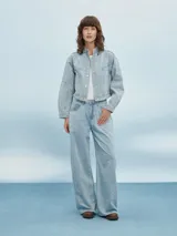 Campera de jean azul claro con cuello mao, cierre con botones metálicos y costuras a contraste.