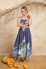 Vestido midi azul con estampado de palmeras y otros motivos tropicales, escote redondo y cinto de rafia.