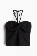 Top corto negro de punto con textura, corte entallado, escote halter y tiras finas con cuentas en los extremos.