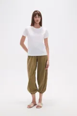 Remera blanca de algodón con cuello redondo y manga corta. Presenta un bordado lineal en tono claro, simulando formas orgánicas o florales, adornado con pequeñas mostacillas.