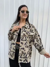 Campera de jean color beige con estampado animal print en tonos marrón y negro. Tiene cuello clásico, cierre frontal con botones, bolsillos con solapa y detalle de flecos en los bordes.