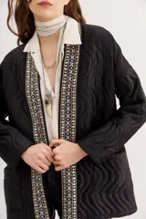 Saco negro acolchado con diseño de ondas y ribete bordado con cuentas.