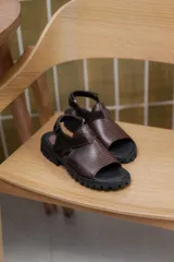Sandalias marrones con tiras de cuero texturizado y suela track negra.
