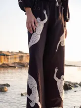 Pantalón palazzo negro con estampado de sirenos blancos y cintura elástica.